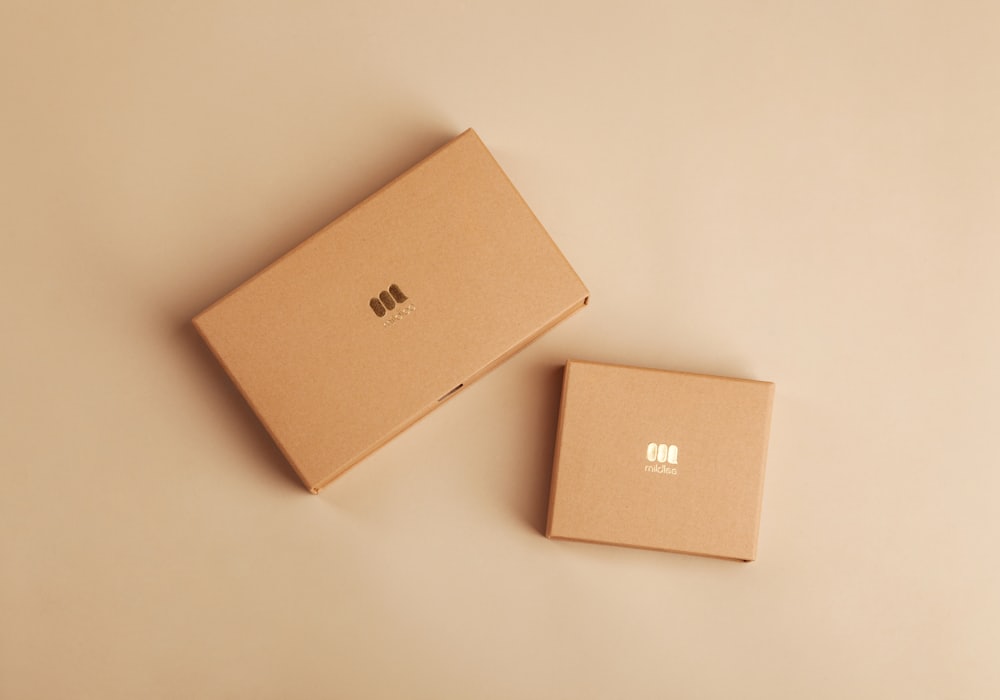 Minimal branded e-commerce packaging photographed on a neutral background.